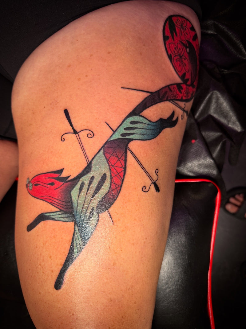 A folk tattoo on a person's thigh depicting a red and blue fox