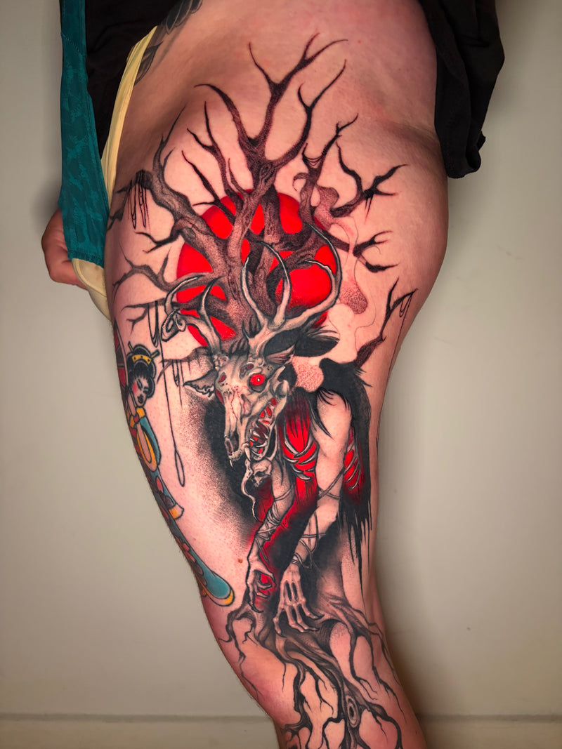 A large, detailed black and red tattoo on a person's upper thigh and upper arm, featuring a wendigo