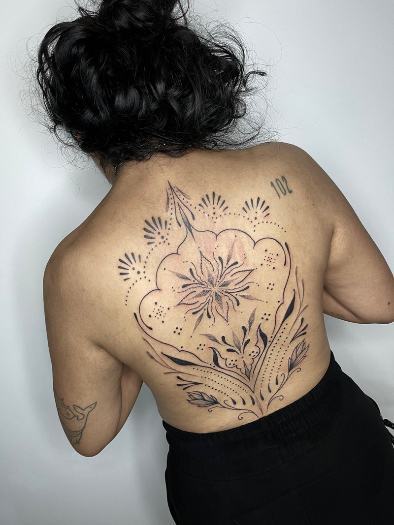 A person shown from the back with a large floral back tattoo 